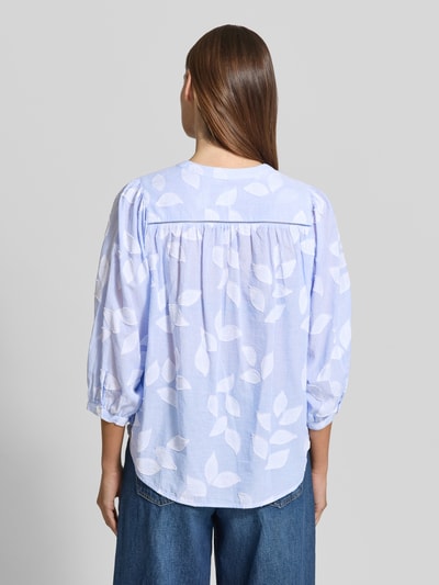 Frauenmodel trägt Regular Fit Bluse mit 3/4-Arm Modell 'FAVIOLA FANCY' von 0039 Italy aus reiner Baumwolle, hinten leicht abgerundet, zartes Hellblau mit weißen Blättermotiven, Ganzkörperansicht Rückansicht.