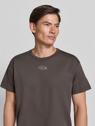 Männermodel trägt Regular Fit T-Shirt aus reiner Baumwolle von Diesel in Dunkelbraun mit Logo-Detail, Nahaufnahme Oberkörper.