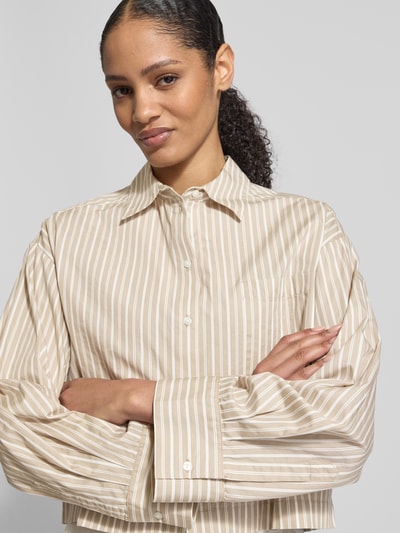 Vrouwenmodel draagt Oversized Hemdbluse aus reiner Bio-Baumwolle Modell 'Astha' van Selected Femme met look: effen, oversized fit, overhemdkraag, knoopsluiting, borstzak, manchetten, webstructuur, biologisch katoen. Nahaufnahme Oberkörper.