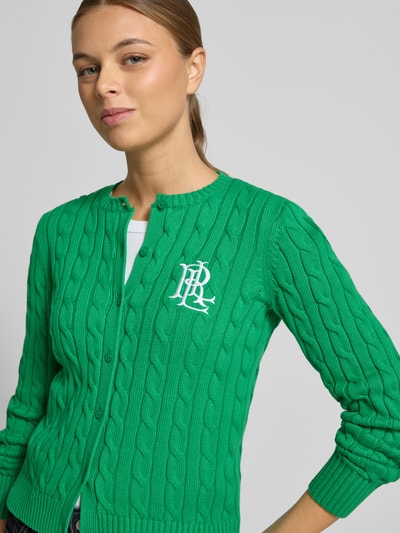 Frauenmodel trägt Strickjacke mit Zopfmuster und Label-Stitching Modell 'RALHAN' von Lauren Ralph Lauren in Grün, Baumwolle, Nahaufnahme Oberkörper.