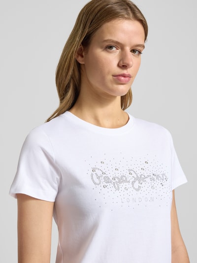 Vrouwenmodel draagt Regular Fit T-Shirt uit pure katoen model 'BRADY' van Pepe Jeans, effen wit met sierstenen en logo, close-up bovenlichaam.