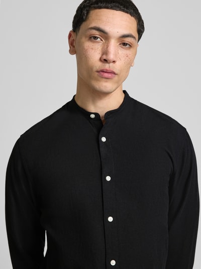 Männermodel trägt schwarzes Freizeithemd mit Stehkragen und Knopfleiste, Baumwoll-Leinen-Mix, Regular-Fit, Modell 'BREEZE' von Jack & Jones, Nahaufnahme Oberkörper.