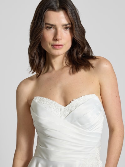 Frauenmodel trägt Brautkleid mit Herz-Ausschnitt von Mascara, Satin, taillierte Passform, floraler Spitzenbesatz, Zierperlen, Nahaufnahme Oberkörper.
