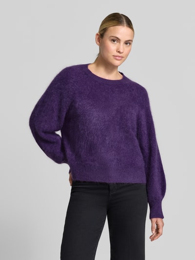 Modelka nosi Regular Fit Pullover aus Kaschmir-Mix mit Woll-Anteil von HERZENS, mieszanka kaszmiru z dodatkiem wełny, imitacja dzianiny, okrągły dekolt, elastyczne wykończenia, długość tyłu 55 cm, długość rękawów 65 cm, fioletowy kolor, widok całej sylwetki z przodu.