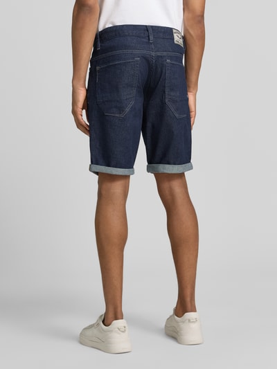 Mannelijk model draagt Regular Fit Jeansshorts im 5-Pocket-Design van PME Legend, donkerblauwe katoen-elastaan mix, model 'NIGHTFLIGHT', knoop- en ritssluiting, maat 32 met taillewijdte 43 cm en binnenbeenlengte 25 cm, geheelopname achteraanzicht.
