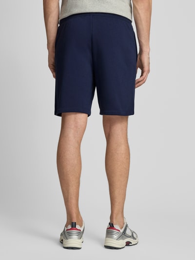 Männermodel trägt Sweatshorts mit elastischem Bund von GAP aus dunkelblauem Baumwoll-Mix, Relaxed-Fit, mit Logo, Ganzkörperansicht Rückansicht.