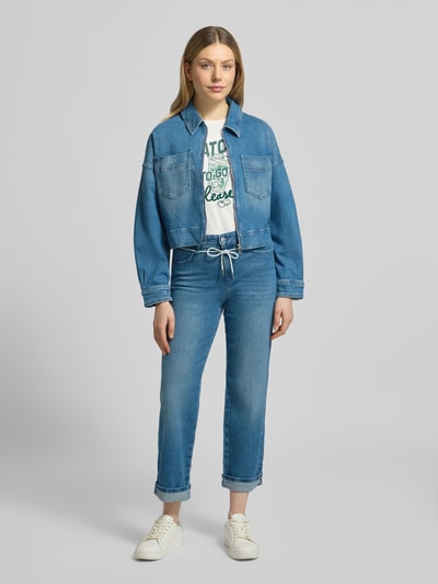 Vrouwenmodel draagt Cropped Jeansjacke aus Baumwoll-Mix van Marc Cain, rechte fit, blauwe denim, borstzakken, taille kort, voorkant, geheellichaamsaanzicht.