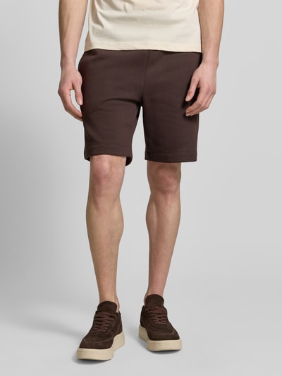 Männermodel trägt Regular Fit Sweatshorts aus Baumwoll-Mix von Lacoste in Braun, unifarben, elastischer Bund, Nahaufnahme Oberkörper bis Knie.