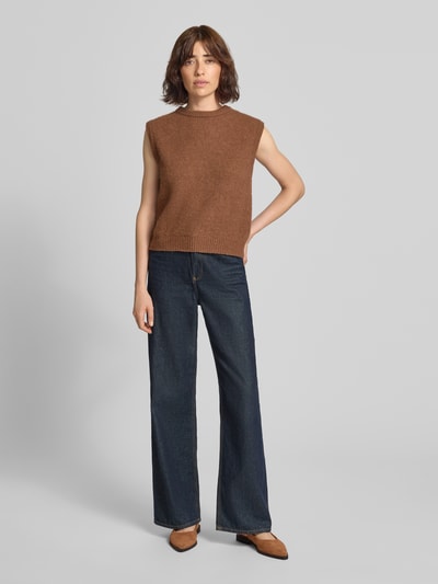 Frauenmodel trägt Pullunder aus Alpaka-Mix mit Rundhalsausschnitt von American Vintage in Braun, kombiniert mit weiter Jeans, gerippte Abschlüsse, Regular Fit, Damenmodell VITOW, Ganzkörperansicht von vorne.