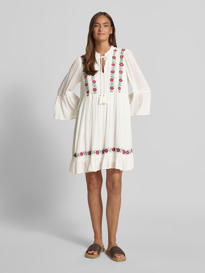 Frauenmodel trägt Tunikakleid mit Stitchings Modell 'CHELLA' von YAS, A-Linie, Minikleid, Schnürung, Weiß mit bunten Details, Ganzkörperansicht von vorne. Rückenlänge bei Größe 36: 36 cm, Brustweite bei Größe 36: 50 cm, Ärmellänge bei Größe 36: 51 cm.