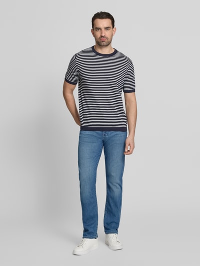Męski model nosi Regular Fit Jeans aus Baumwoll-Mix von Tommy Hilfiger, stylizowana na denim, krój regular fit, naszywka z logo, nity, wyhaftowane logo, szlufki na pasek, zapięcie na guzik i kryty zamek błyskawiczny, 5 kieszeni, mieszanka bawełny, całkowity widok z przodu.
