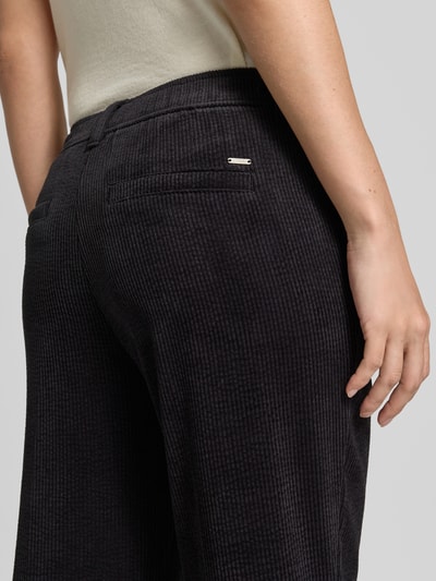 Frauenmodel trägt Cordhose mit elastischem Bund von Christian Berg Woman, schwarze Farbe, feine Cordstruktur, Nahaufnahme Hüfte, Material-Mix mit Stretch-Anteil, angedeutete Gesäßleistentaschen