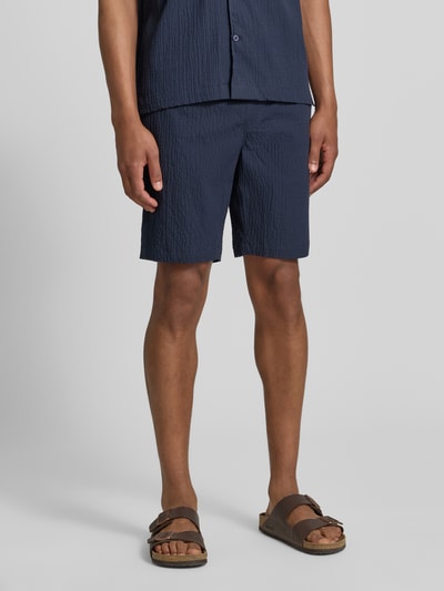 Männermodel trägt Shorts mit elastischem Bund und Strukturmuster von Lindbergh, Baumwoll-Mix mit Stretch-Anteil, Loose-Fit, Nahaufnahme Oberkörper.