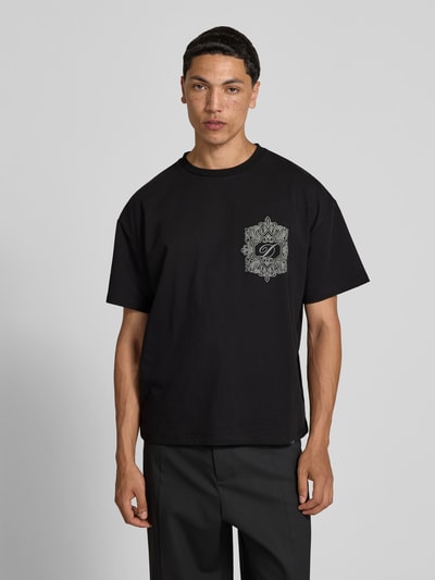 Männermodel trägt Regular Fit T-Shirt aus Baumwoll-Mix von Don’t Waste Culture, Schwarz, Rundhalsausschnitt, Label-Detail, Kurzärmelig, Ganzkörperansicht von vorne.