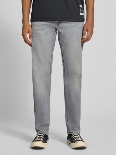 Męski model nosi Straight Fit Jeans mit Stretch-Anteil Modell 'MIKE' von JACK & JONES, mieszanka bawełny i elastanu, 5 kieszeni, szare odcienie, zapięcie na guzik i zamek błyskawiczny, szerokość w rozmiarze 32/32: 44 cm, długość wewnętrzna nogawki: 78 cm, pełny widok z przodu.