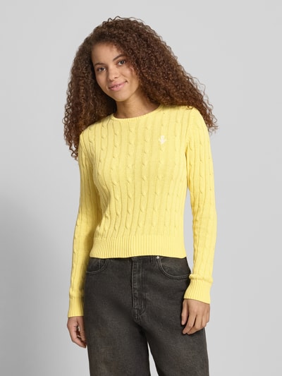 Frauenmodel trägt Strickpullover mit Zopfmuster und Label-Stitching von REVIEW in Gelb aus Baumwoll-Mix, Regular-Fit, Rundhalsausschnitt, Nahaufnahme Oberkörper.