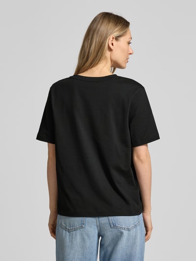 Frauenmodel trägt Relaxed Fit T-Shirt aus reiner Baumwolle von Lacoste in Schwarz, unifarben, Logo-Stitching, Rückansicht Ganzkörperansicht.
