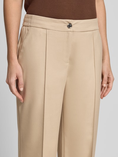 Frauenmodel trägt Stoffhose mit Bügelfalte Modell 'Melane' von OPUS in Beige, Material-Mix mit Viskose-Anteil, Nahaufnahme Oberkörper.