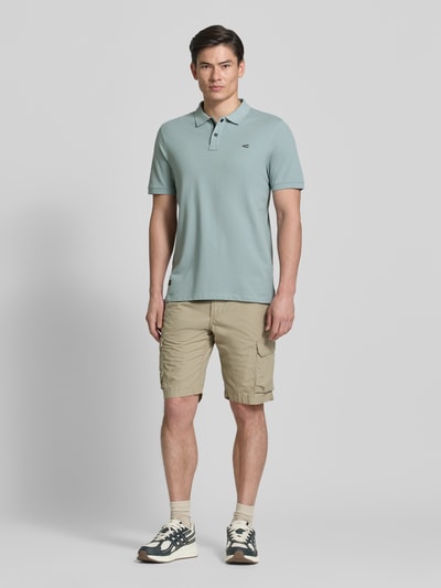 Mannelijk model draagt Regular Fit Poloshirt in unifarbenem Design van camel active, katoen-elastaanmix, knoopsluiting, logodetail, unikleuren, vooraanzicht volledig lichaam