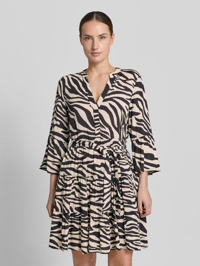 Vrouwenmodel draagt tailliertes Tunikakleid aus reiner Viskose Modell 'MELBA' van Vero Moda met all-overprint, getailleerde fit, mini-lengte, v-hals, ceintuurlussen, strikriem, trompetmouwen, volantzoom, lichte stof met zebra-patroon, Vooraanzicht buste-close-up.