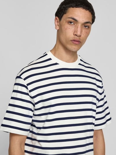 Männermodel trägt T-Shirt mit Rundhalsausschnitt von Filippa K, Reine Baumwolle, Relaxed-Fit, Streifenmuster, Kurzärmelig, Nahaufnahme Oberkörper.