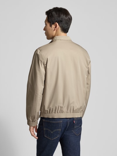 Männermodel trägt Jacke mit Stehkragen und Reißverschluss von CK Calvin Klein in Beige, Regular Fit, Rückansicht, Ganzkörperansicht. Rückenlänge 65 cm, Schulterbreite 46 cm, Brustweite 57 cm, Ärmellänge 67 cm, glatte Textur, Eingrifftaschen.
