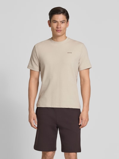 Männermodel trägt Regular Fit T-Shirt aus Baumwoll-Mix Modell 'AUSTIN' von HUGO, beige, Waffelstruktur, unifarben, Ganzkörperansicht von vorne.