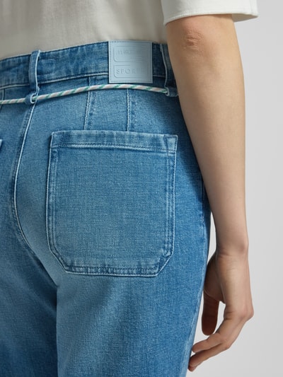 Kobiece model prezentuje Straight Fit Jeans mit fixierten Beinabschlüssen od Marc Cain, jasnoniebieski, bawełna elastyczna, detal tylnych kieszeni, zbliżenie na biodra, widok z tyłu.