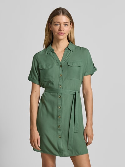 Frauenmodel trägt Fließendes Freizeitkleid aus reiner Viskose Modell 'BUMPY' von Vero Moda, Optik: Unifarben, Passform: fließend, Mini-Länge, V-Ausschnitt, Rückenpasse, Knopfleiste, Ärmelform: Kurzarm, Materialverarbeitung: Popeline, Material: reine Viskose, Ganzkörperansicht von vorne.