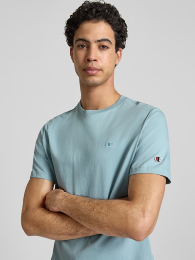 Mannenmodel draagt T-shirt met labelstitchings en ronde hals van CHAMPION, puur katoen, regular fit, ruglengte maat M 66 cm, nahaufnahme bovenlichaam.