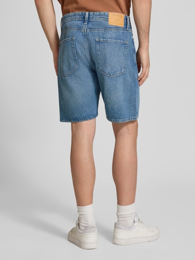 Männermodel trägt Loose Fit Jeansshorts mit Eingrifftaschen Modell 'TONY' von Jack & Jones, blaue Baumwolle, Used-Look, Ganzkörperansicht Rückansicht.