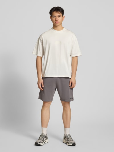 Männermodel trägt Regular Fit Shorts mit Label-Stitching von REVIEW in Grau, Baumwoll-Mix, elastischer Bund, Ganzkörperansicht von vorne.