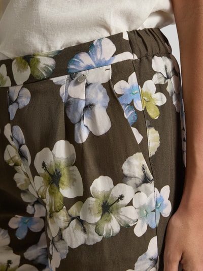 Frauenmodel trägt Hose aus Viskose-Leinen-Mix Modell 'Alexandria' von STEHMANN im Allover-Look, Nahaufnahme Hüftbereich, verkürzte Passform, Bundweite 38 cm, Innenbeinlänge 68 cm, Größe 36, florales Muster, glatte und leichte Textur.