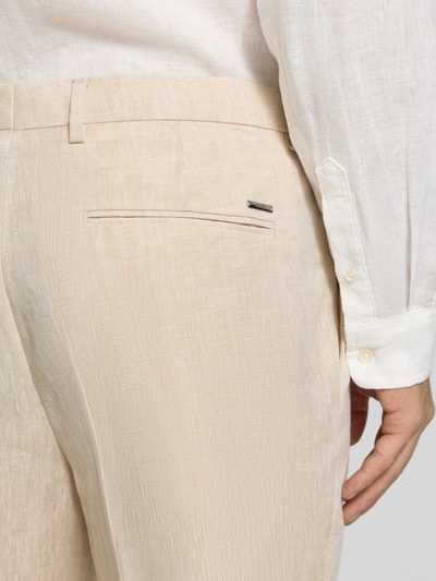 Mężczyzna nosi Tapered Anzughose aus reinem Leinen Modell 'H-PERIN' von BOSS, beżowa melanżowa tekstura, detal metalowej aplikacji z tyłu, krój tapered fit, materiał len, detalaufnahme tylnych kieszeni.