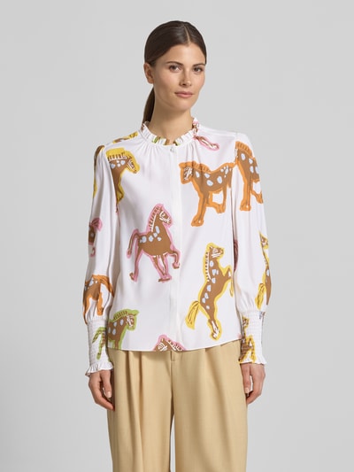 Frauenmodel trägt Bluse mit Rüschen und Smok-Details von HERZENS, Gerader-Schnitt, Rundhalsausschnitt, Cremetöne und bunte Pferde, verdeckter Verschluss, Smok-Details an Ärmeln, Rückenlänge 28 cm, Ärmellänge 64 cm, Ganzkörperansicht von vorne.