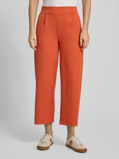 Vrouwenmodel draagt Wide Fit Stoffhose mit Viskose-Anteil Modell 'Kate' van ICHI in oranje, met elastische tailleband en plooien, Ganzkörperansicht van voren.