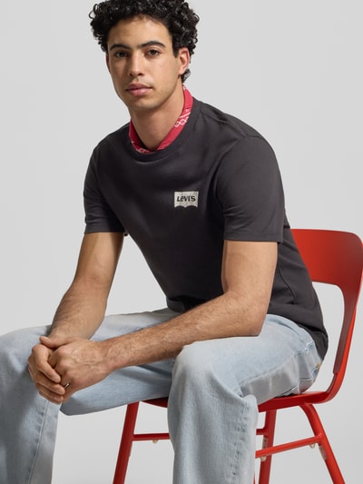 Męski model nosi T-shirt mit Label-Print von LEVI'S®, bawełna, krój regular fit, okrągły dekolt, nadruk z logo, długość tyłu 73 cm, rozmiar M, zbliżenie na górną część ciała.