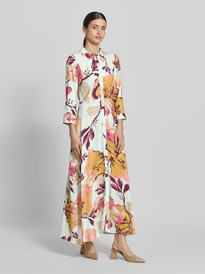 Modelka kobieca nosi Hemdblusenkleid aus Viskose mit Knopfleiste Modell 'SAVANNA' od YAS, jasne kolory, motyw kwiatowy, A-linia, długość maxi, czysta wiskoza, całkowity nadruk, długość tyłu w rozmiarze S: 140 cm, szerokość w rozmiarze S: 47 cm, długość rękawa w rozmiarze S: 49 cm, widok całej sylwetki z przodu