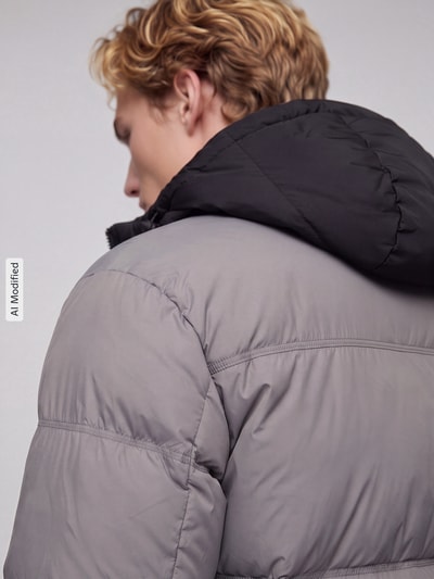 Männermodel trägt Regular Fit Steppjacke mit Kapuze Modell 'Bodo2541' von HUGO w dwukolorowy, popelina, hydrofobowy, naszywka z logo, Ganzkörperansicht Rückansicht, KI-modifiziertes Bild.