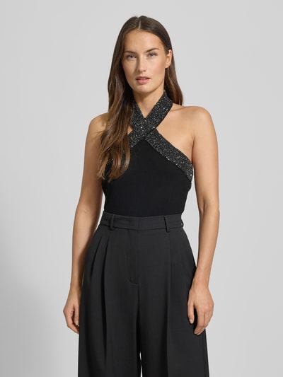 Frauenmodel trägt Blusentop mit Neckholder von Mango, Schwarz, Viskose-Mix, Slim-Fit, Paillettenbesatz, Rückenlänge 30 cm, Nahaufnahme Oberkörper.
