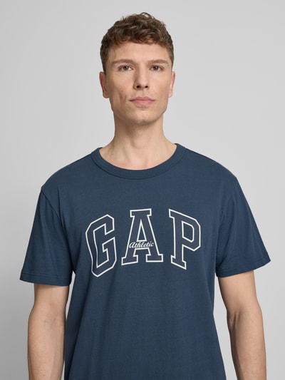Männermodel trägt T-Shirt mit Logo und Rundhalsausschnitt von GAP in Dunkelblau, Reine Baumwolle, Regular-Fit, Nahaufnahme Oberkörper.