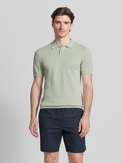 Männermodel trägt Slim Fit Poloshirt in Strick-Optik Modell 'TRITON' von Drykorn aus Baumwolle, hellgrün, Ganzkörperansicht von vorne.