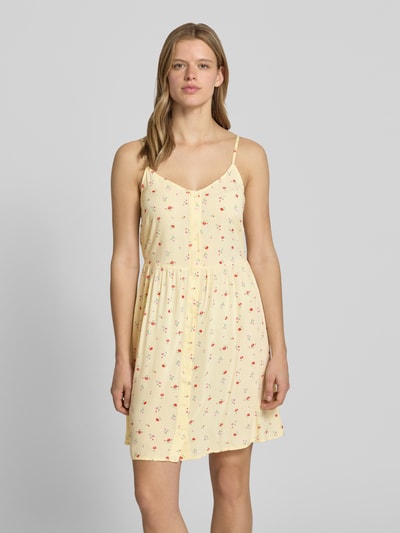 Frauenmodel trägt Leicht ausgestelltes Minikleid aus reiner Viskose Modell 'TALA' von Pieces mit Florales-Allover-Muster in Gelb, V-Ausschnitt, Trägerform:verstellbare Spaghettiträger, Ärmelform:Ohne, Saum:Gerade, Material:Reine Viskose, Ganzkörperansicht von vorne.