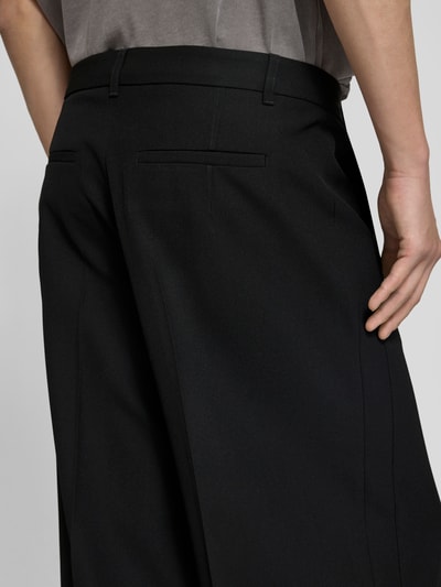 Männermodel trägt Wide Fit Leinenhose mit Gesäßtaschen von WON HUNDRED, schwarzer Stoff, Bügelfalten, Detailaufnahme Rückansicht.
