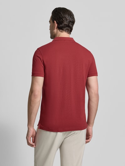 Männermodel trägt Slim Fit Poloshirt mit Logo-Stitching von MCNEAL in Rot, glatte Baumwollstruktur, Ganzkörperansicht Rückansicht.