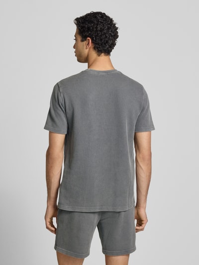Männermodel trägt T-Shirt mit Strukturmuster und Label-Stitchings von CHAMPION in Grau aus Baumwoll-Mix, Regular-Fit, Rückenlänge 68 cm, Ganzkörperansicht Rückansicht.