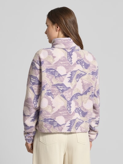 Modelka nosi Regular Fit Pullover mit Logo-Patch Modell 'Helvetia' od Columbia w kolorach fioletowym, beżowym i kremowym, wykończenie fleece, krótka długość pleców 55 cm, szerokość ramion 44 cm, szerokość w rozmiarze S 58 cm, długość rękawa 58 cm, detal: naszywka z logo, kieszeń na piersi z zamkiem, elastyczne mankiety, listwa guzikowa, stójka, widok całej sylwetki od tyłu.