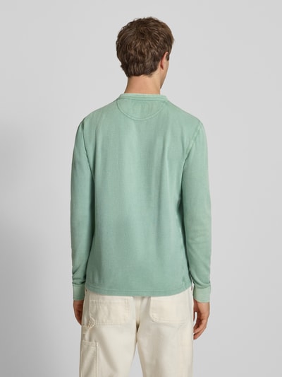 Mężczyzna nosi Longsleeeve mit Knopfleiste von Superdry w zielonym kolorze, czysta bawełna, krój regular fit, długość tyłu w rozmiarze M: 72 cm, widok całej sylwetki z tyłu