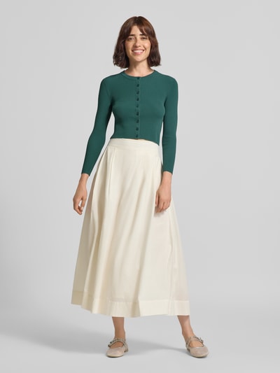 Frauenmodel trägt Slim Fit Strickjacke aus Viskose-Mix Modell 'WKDTENNIS' von Max Mara in Dunkelgrün, kombiniert mit hellem Rock, Damen Strickjacke von Weekend Max Mara, Ganzkörperansicht von vorne.