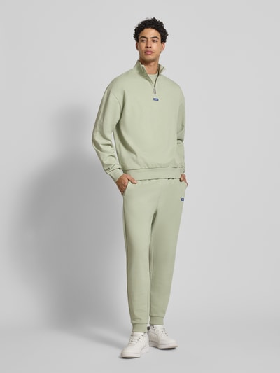 Męski model nosi Regular Fit Troyer aus reiner Baumwolle Modell 'NEELER' von Hugo Blue, jasnozielony, jednolity, długi rękaw, ściągacze, label patch, label stitching, kołnierz troyer, zamek błyskawiczny, materiał sweat z bawełny, krój regular fit; widok całej sylwetki z przodu.